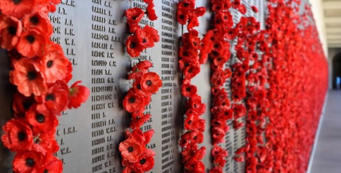 A memorial wall with poppies